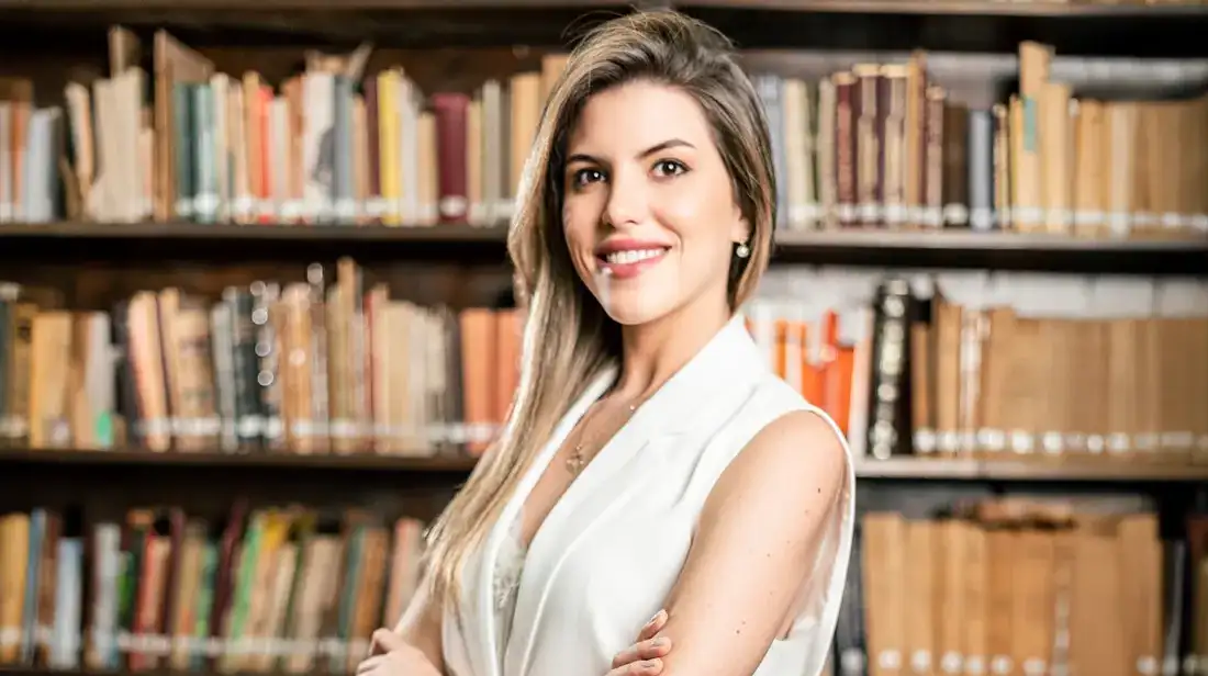 Jimena Irun en la biblioteca del estudio, frente a libros de leyes simbolizando el cumplimiento normativo en derecho laboral.