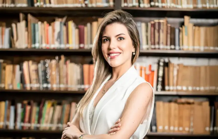 Jimena Irun en la biblioteca del estudio, frente a libros de leyes simbolizando el cumplimiento normativo en derecho laboral.