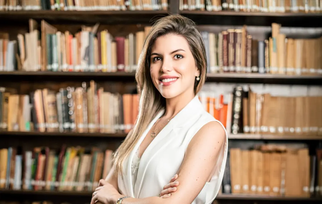 Jimena Irun en la biblioteca del estudio, frente a libros de leyes simbolizando el cumplimiento normativo en derecho laboral.